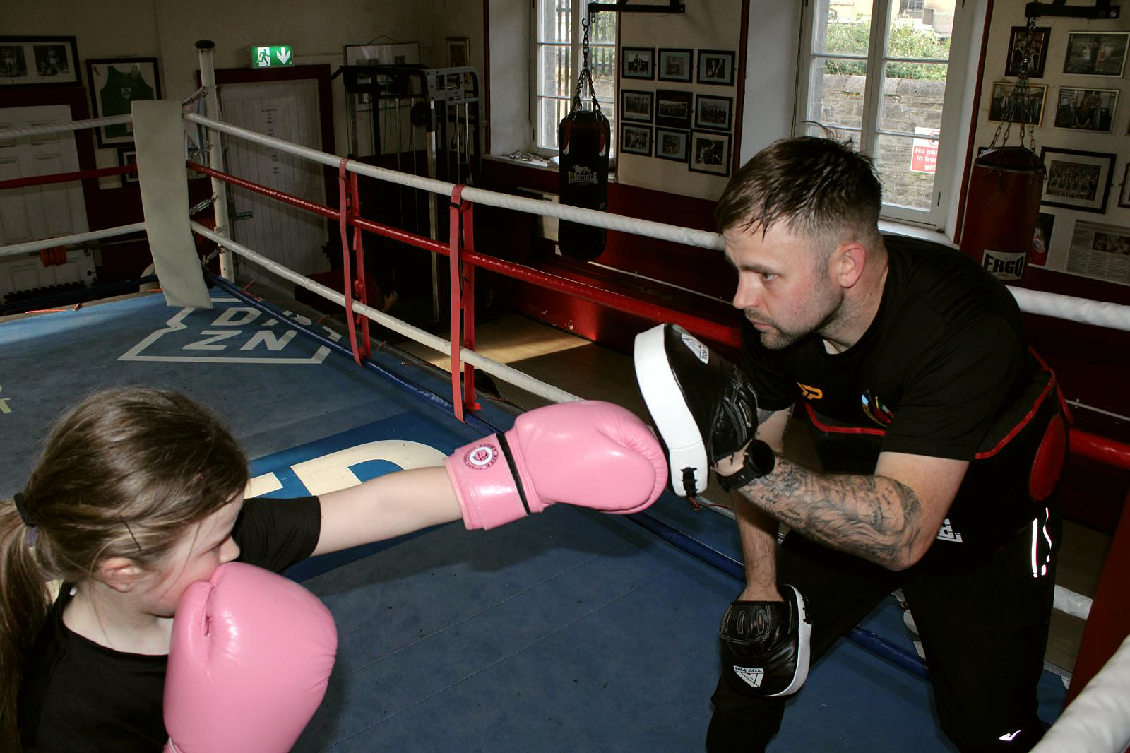 A young girl in pink gloves throwing a jab into a coach's pad in the Arbour Hill ring