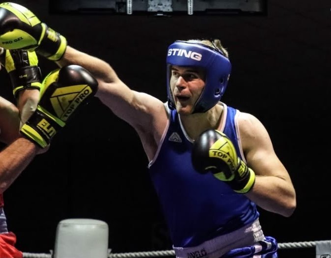 A club boxer in blue landing a jab during a bout