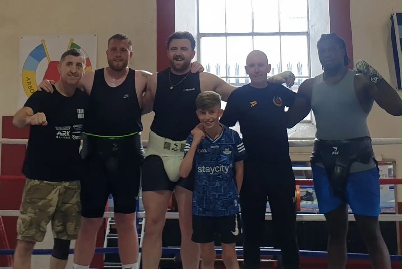 Six senior members and one of the youngest, arms around each other in the ring after training