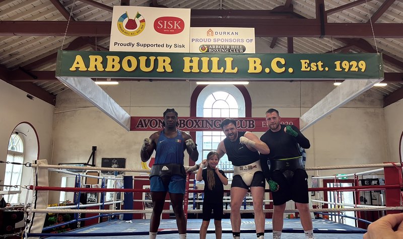 Four members of the club in the ring beneath the hand-painted Arbour Hill B.C. Est. 1929 sign